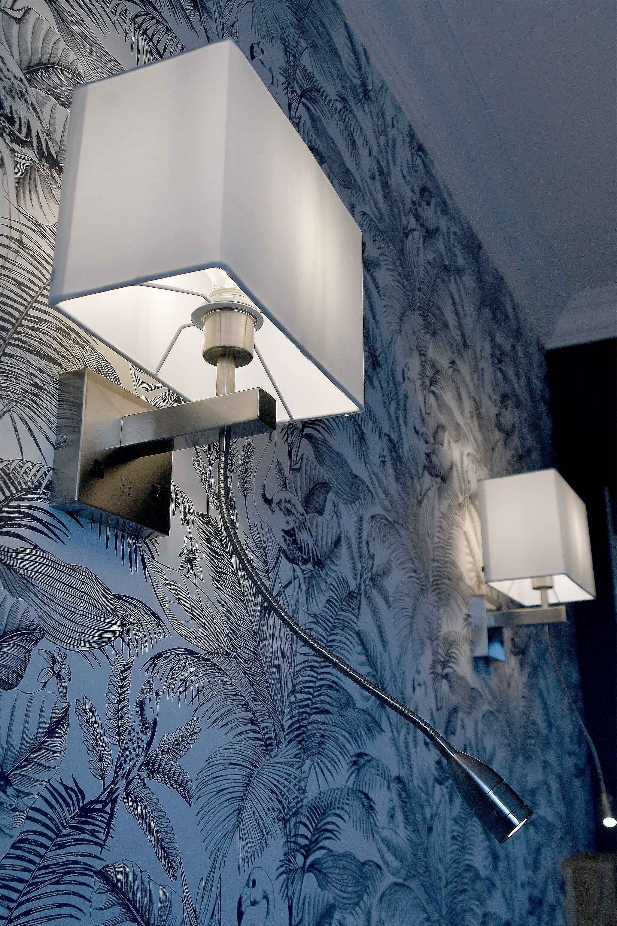 A room with a patterned wallpaper and two wall-mounted lamps.