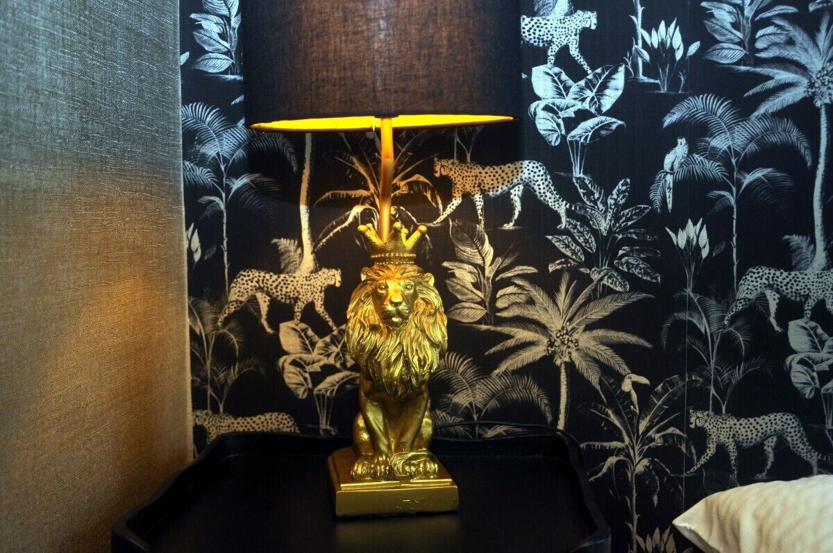 A room with a decorative lamp featuring a lion statue and a patterned wallpaper with animal prints.