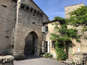 Un edificio in pietra con un ingresso ad arco, un piccolo portico con una porta e una finestra con persiane.