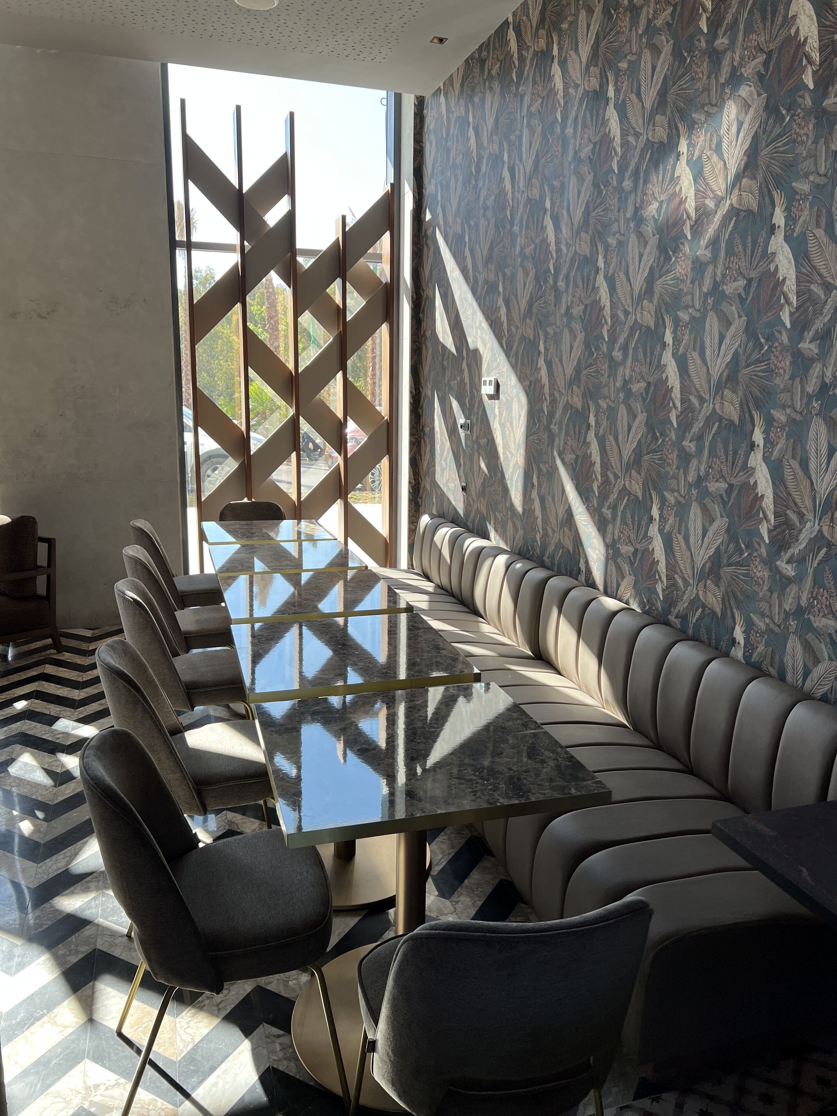 Un salón de conferencias con una mesa de vidrio, un sofá tapizado en gris y papel tapiz estampado.