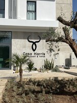 Um edifício moderno com um logotipo de touro e a inscrição "Caza Harris Restaurant & Tapas" na fachada.
