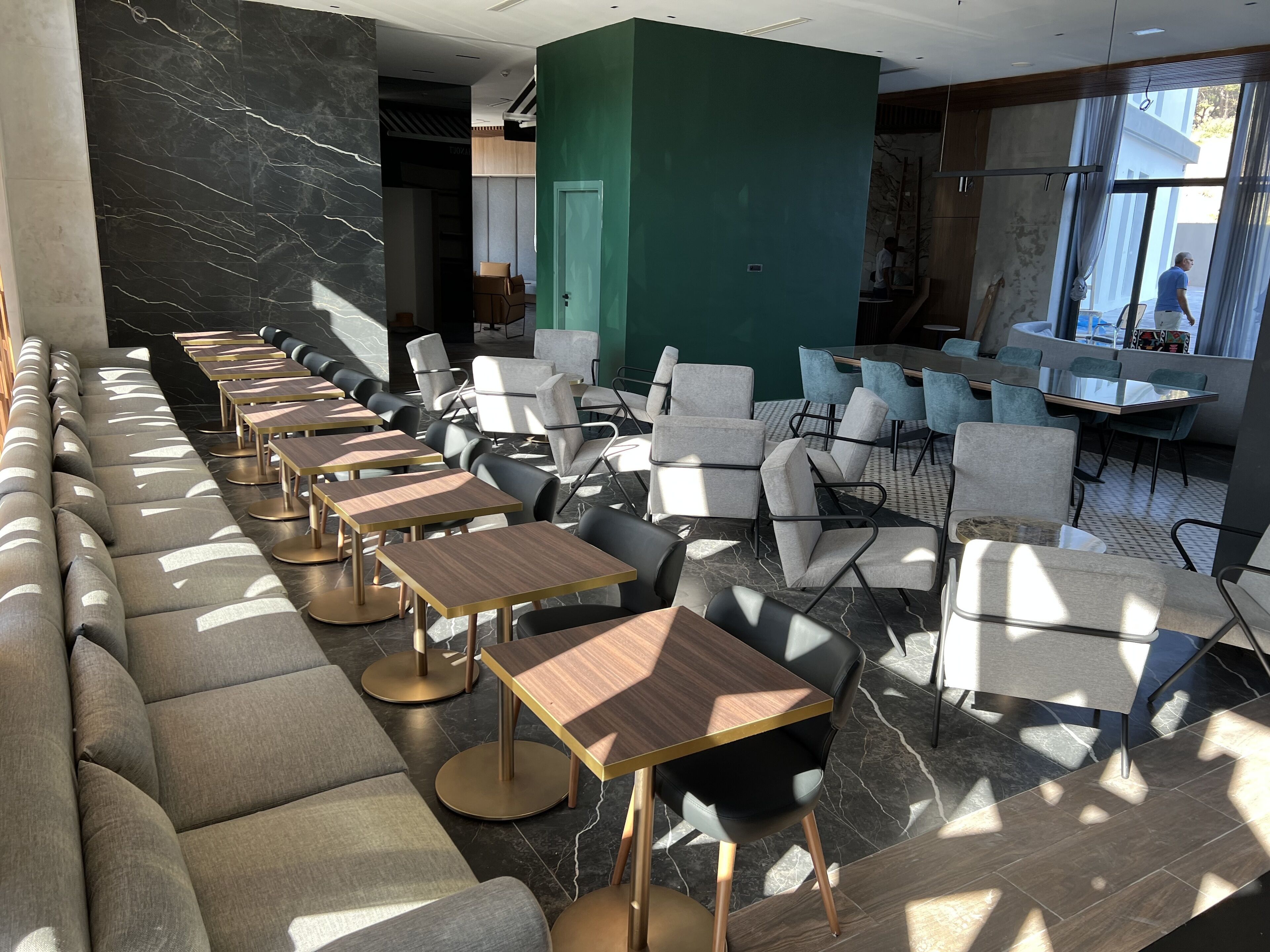 A modern restaurant with a long counter, cushioned seating, and a mix of chairs and tables.