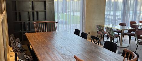 Un comedor moderno con una gran mesa de madera, sillas estampadas y una cabeza de toro decorativa en la pared.