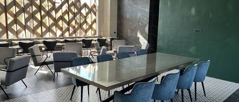 Una sala de conferencias moderna con una mesa de vidrio, sillas azules y baldosas de suelo con diseño.