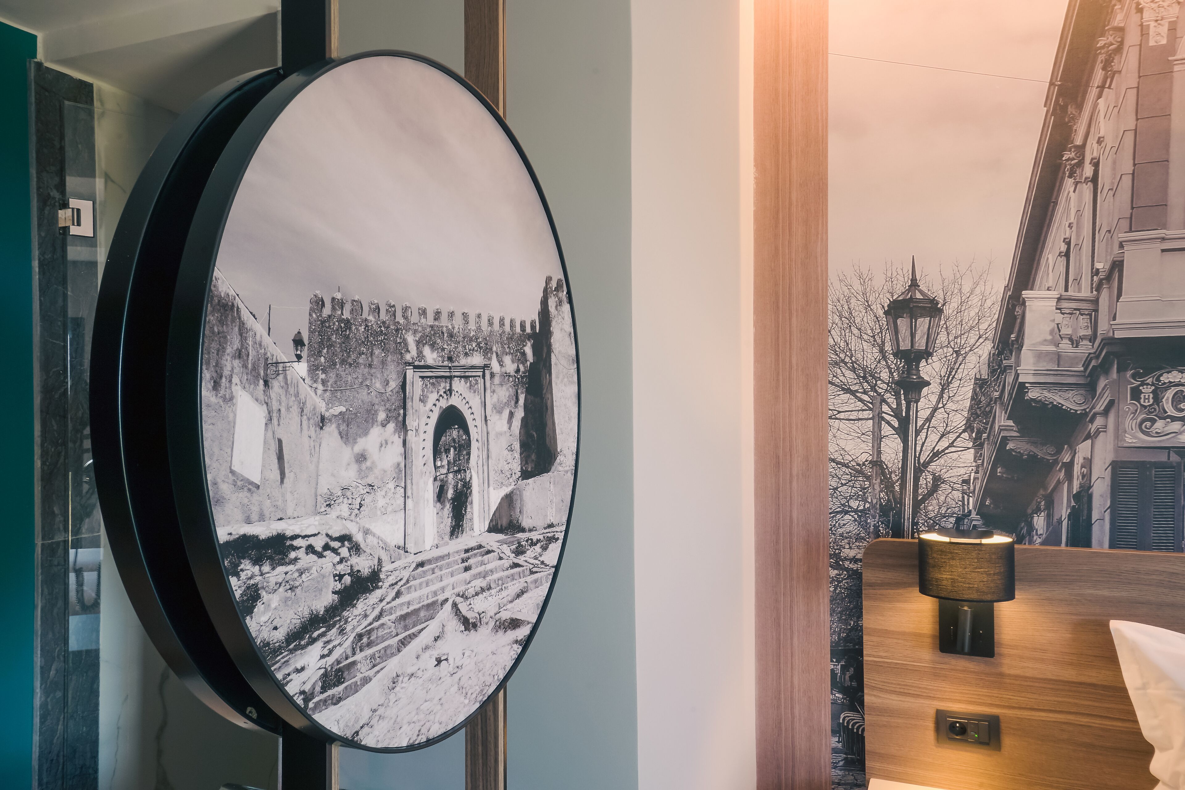 Un espejo redondo con una fotografía blanco y negro de un arco histórico.