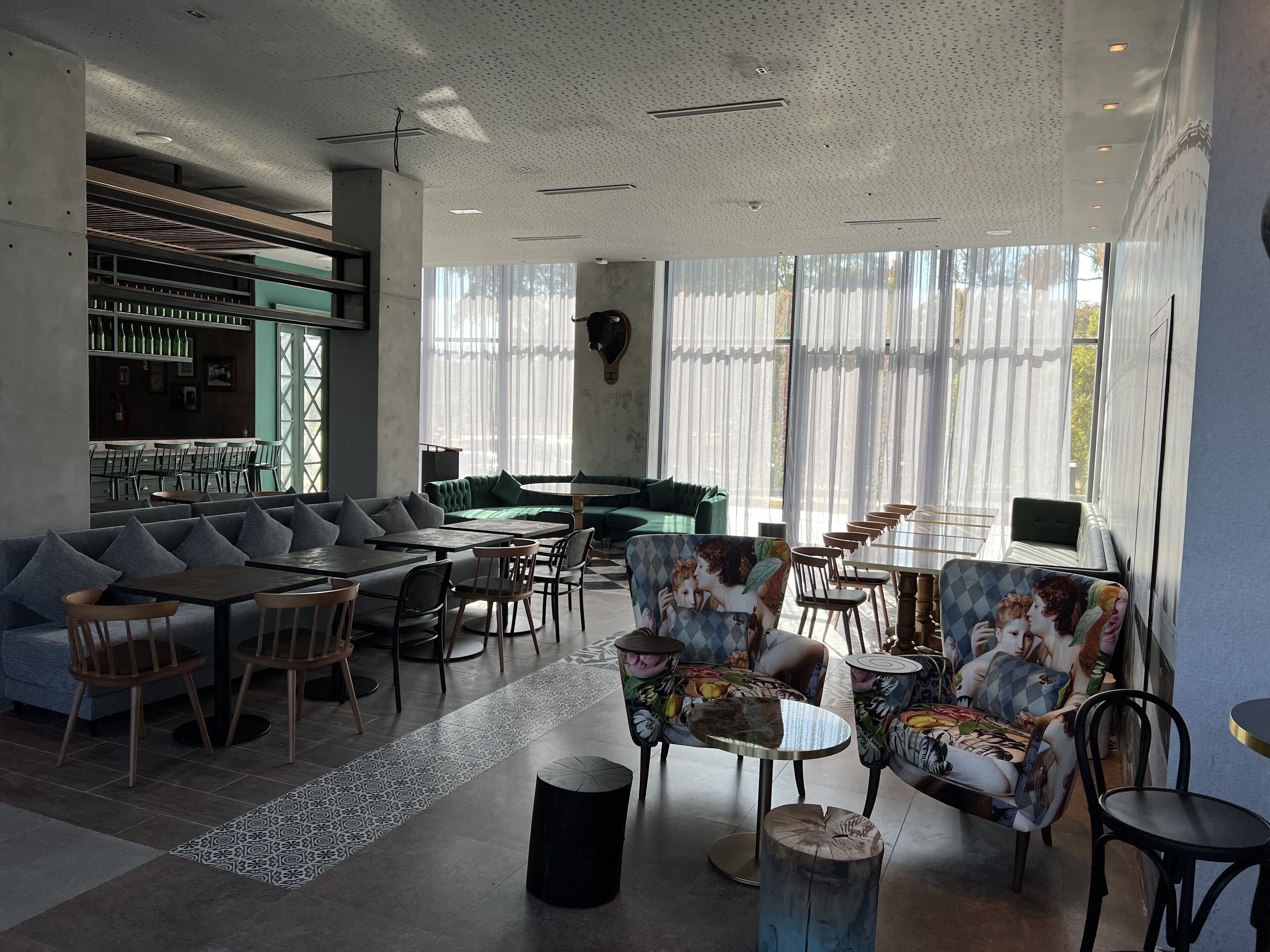 A modern interior with a bar area, seating arrangements, and large windows.