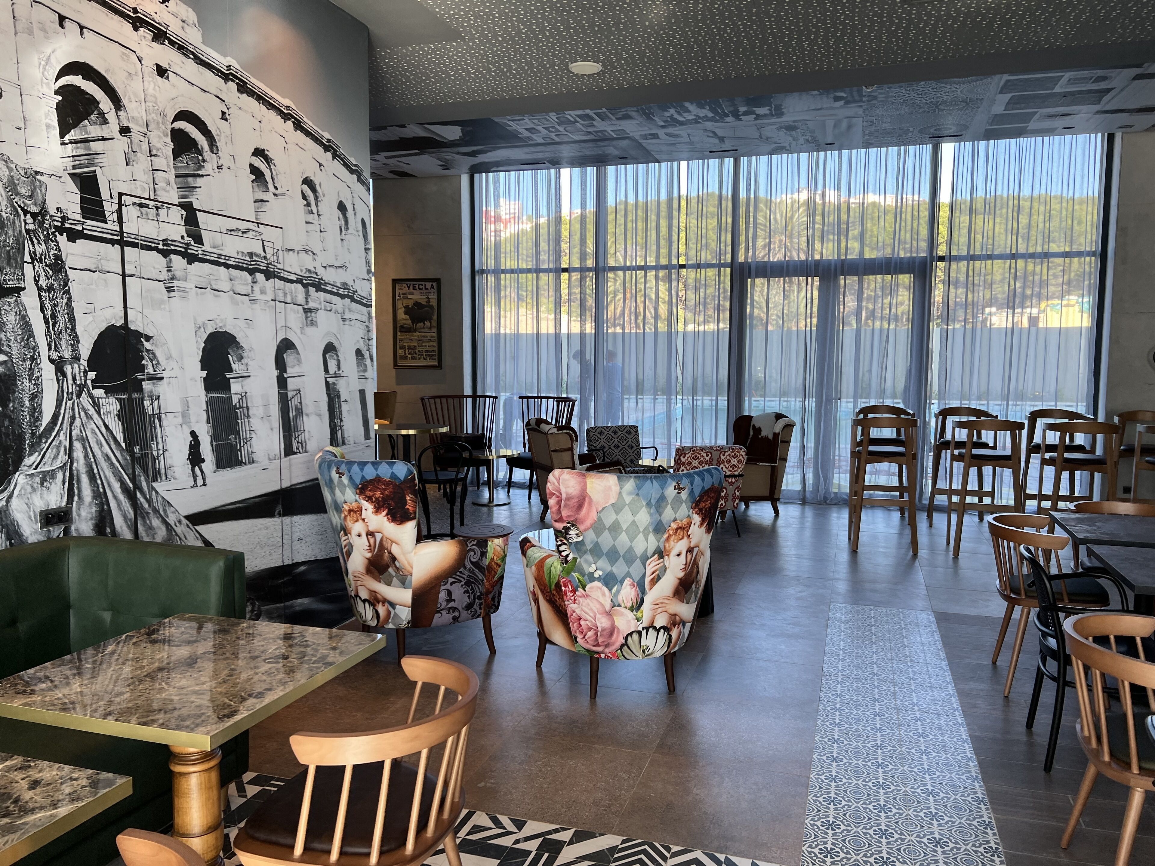 A spacious dining area with high ceilings, large windows, and a mural of a historical building.