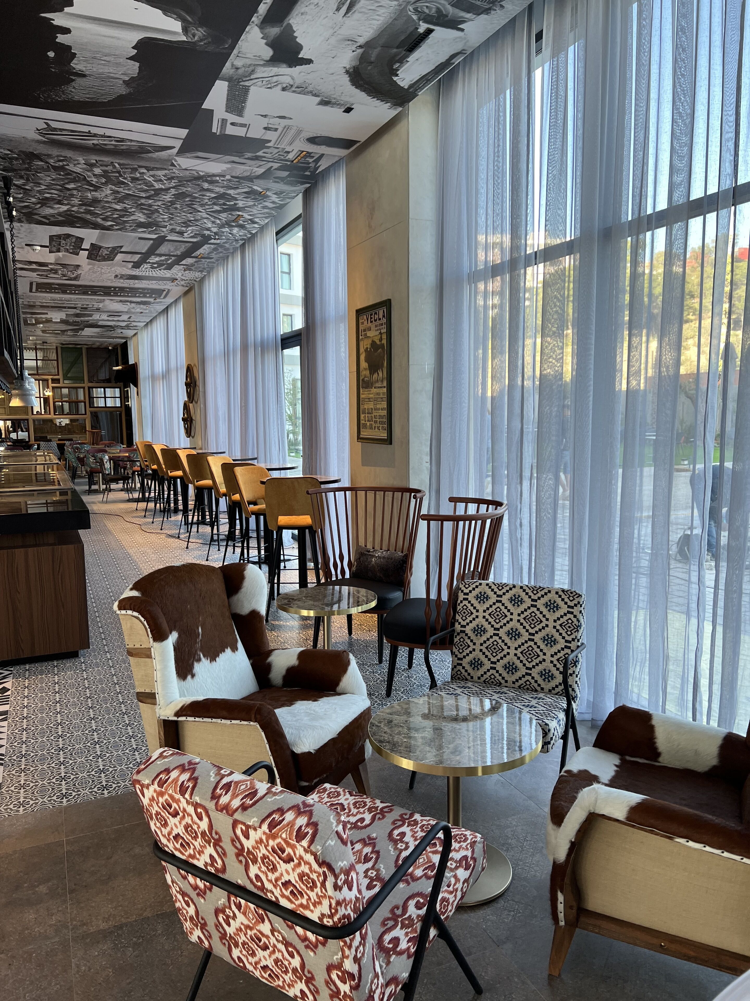 A spacious lounge area with leather sofas, patterned chairs, and a bar area.