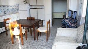 Un espace de vie compact comprenant un coin repas, un canapé, un téléviseur et une cuisine.