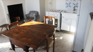Une cuisine avec une table et des chaises en bois, une cuisinière, un réfrigérateur et un évier.