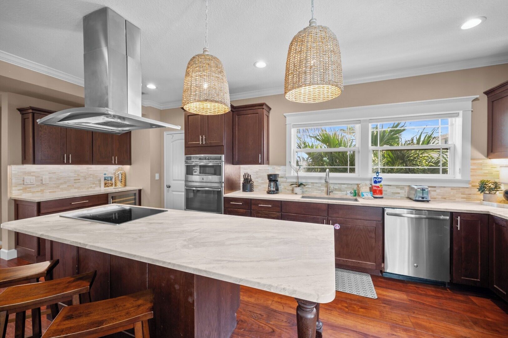 A kitchen with a central island, stainless steel appliances, wooden cabinets, and pendant lighting.