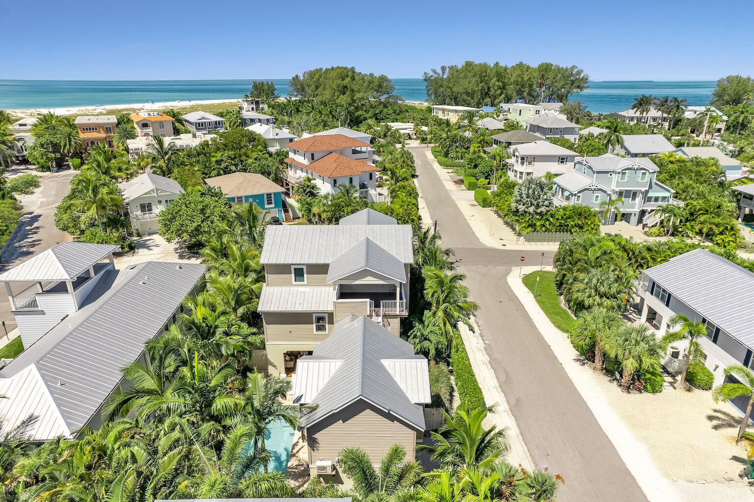 A residential area with houses, a street, and a beach in the background.