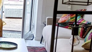 A room with a bed, a table, a colorful rug, and a view of the outside. - Coup de Coeur-Trés bel Appartement avec Terrasse sur le PORT de ST Goustan-Auray (AURAY)