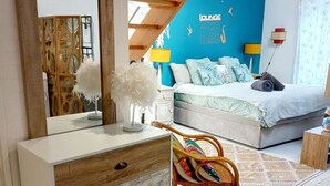 A bedroom with a bed, a dresser, a chair, a mirror, and a blue accent wall. - Coup de Coeur-Trés bel Appartement avec Terrasse sur le PORT de ST Goustan-Auray (AURAY)