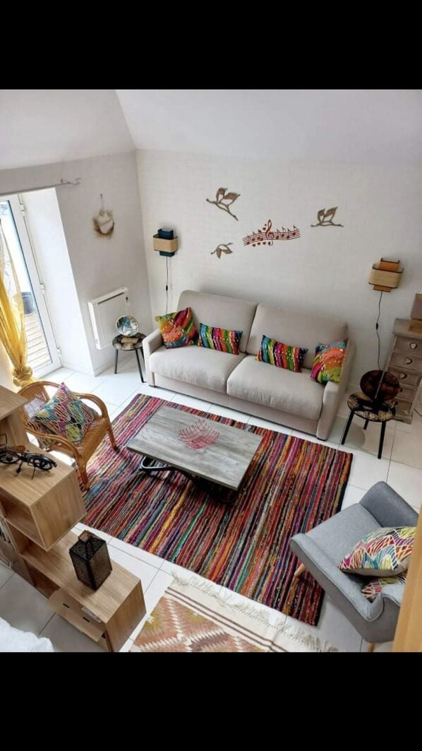 A modern living room with a sofa, colorful pillows, a coffee table, and a patterned rug.