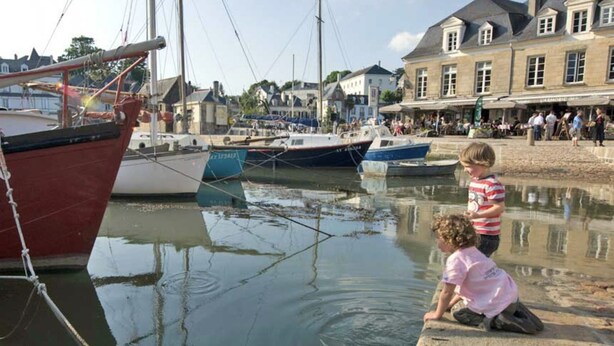 A harbor with boats docked, a building with a sign, and people in the background. - Coup de Coeur-Trés bel Appartement avec Terrasse sur le PORT de ST Goustan-Auray (AURAY)