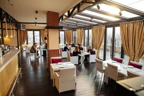 Ein Restaurant mit hohen Decken, großen Fenstern und einer Bar.