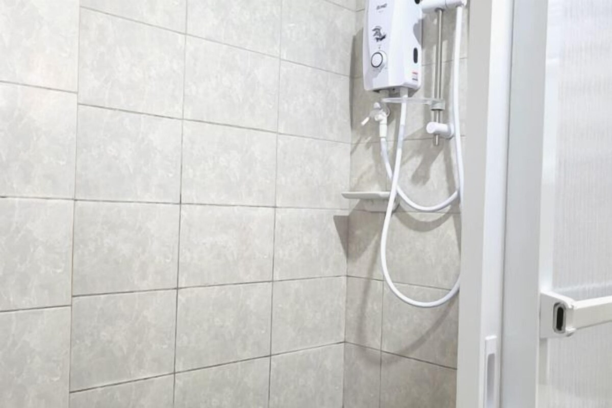 Een badkamer met een douche, betegelde wanden en een witte deur.