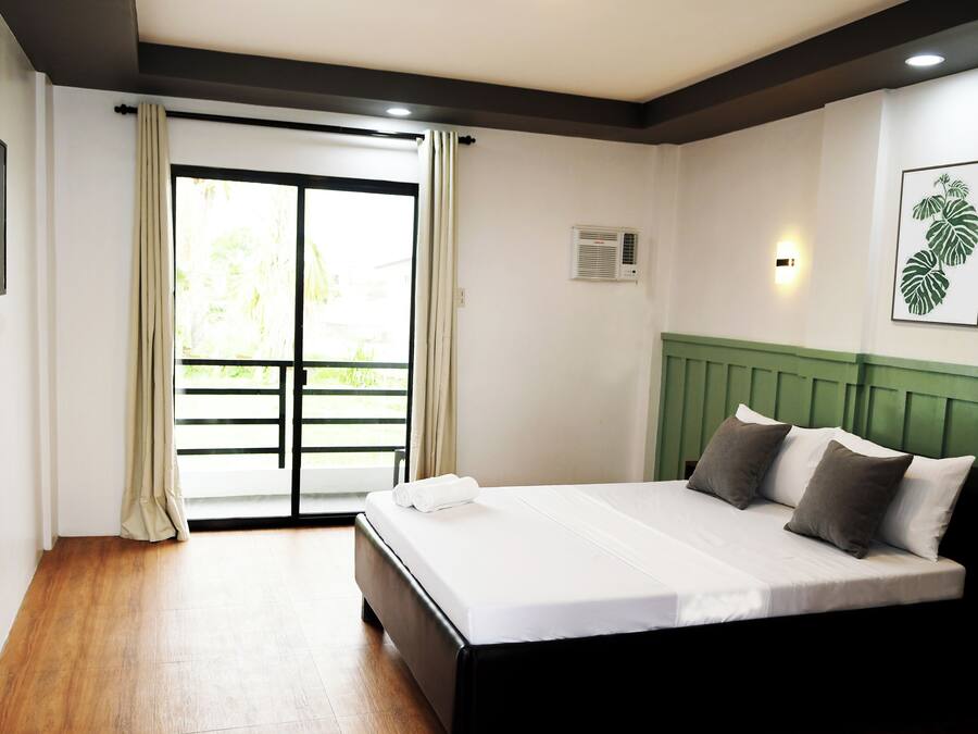 Quarto de hotel com uma cama, porta de correr para uma varanda, televisão de tela plana e ar-condicionado fixado na parede.