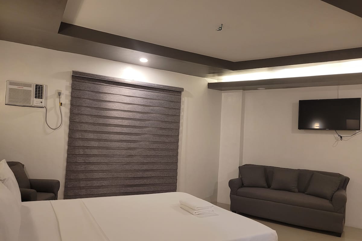 Ein modernes Hotelzimmer mit Bett, Sofa, Fernseher und Wandheizung.