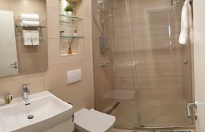 Une salle de bain moderne avec une douche à parois de verre, un lavabo blanc et un miroir.