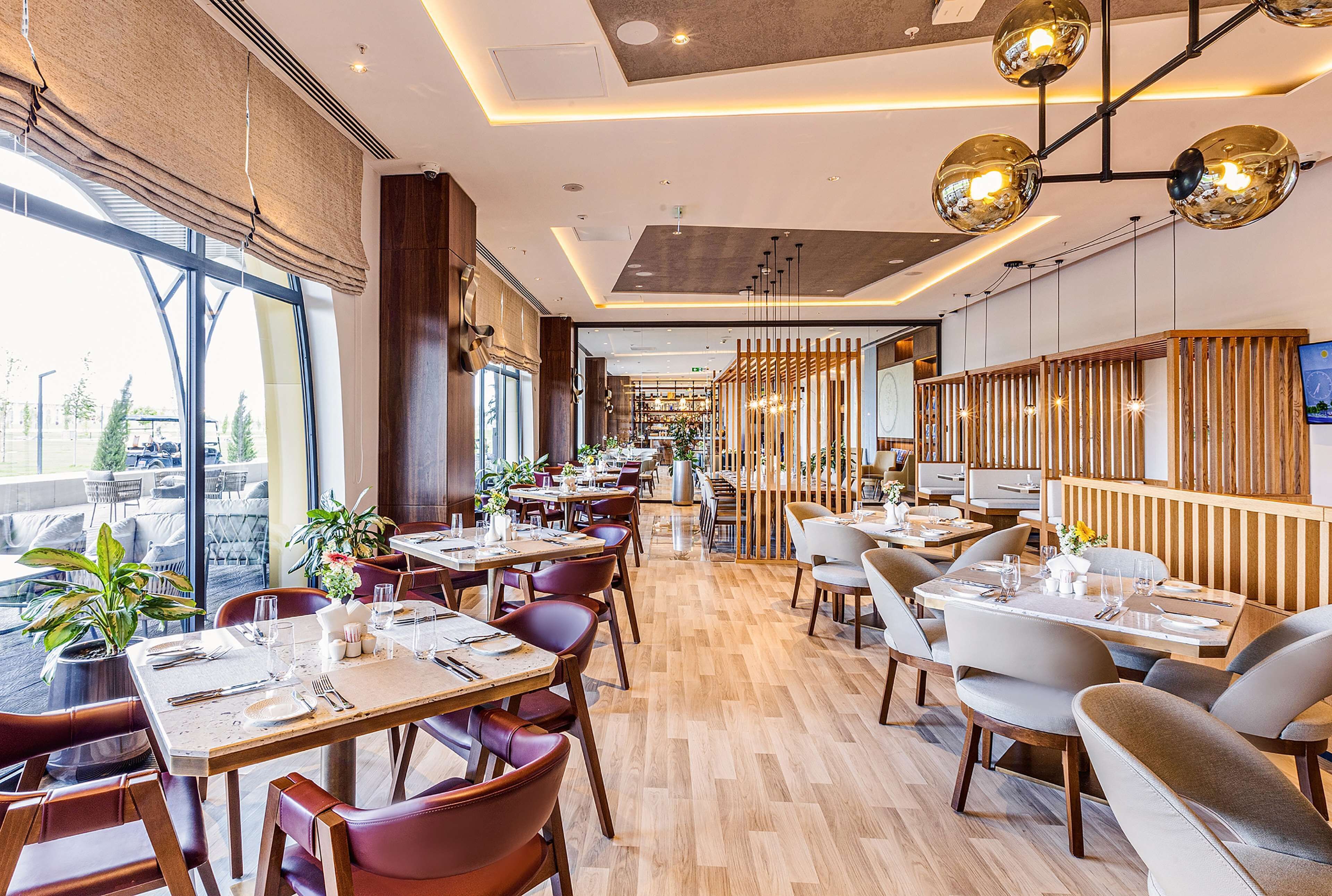 Un intérieur de restaurant moderne avec un plancher en bois, plusieurs tables et chaises.