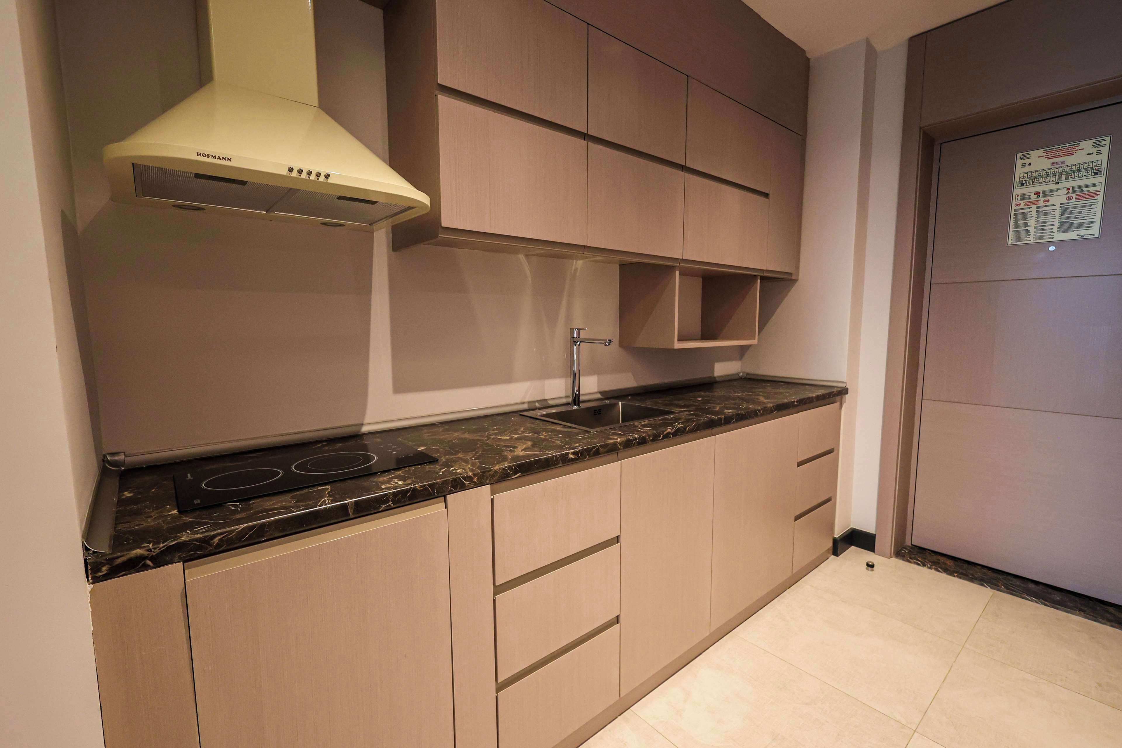 A kitchen with beige cabinets, a black countertop, and a built-in stove.
