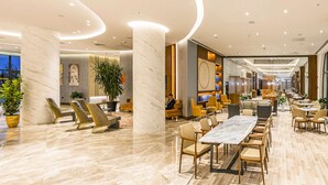 A spacious lobby with marble flooring, seating areas, and a long dining table. - Hilton Garden Inn Samarkand Afrosiyob (Samarkand)