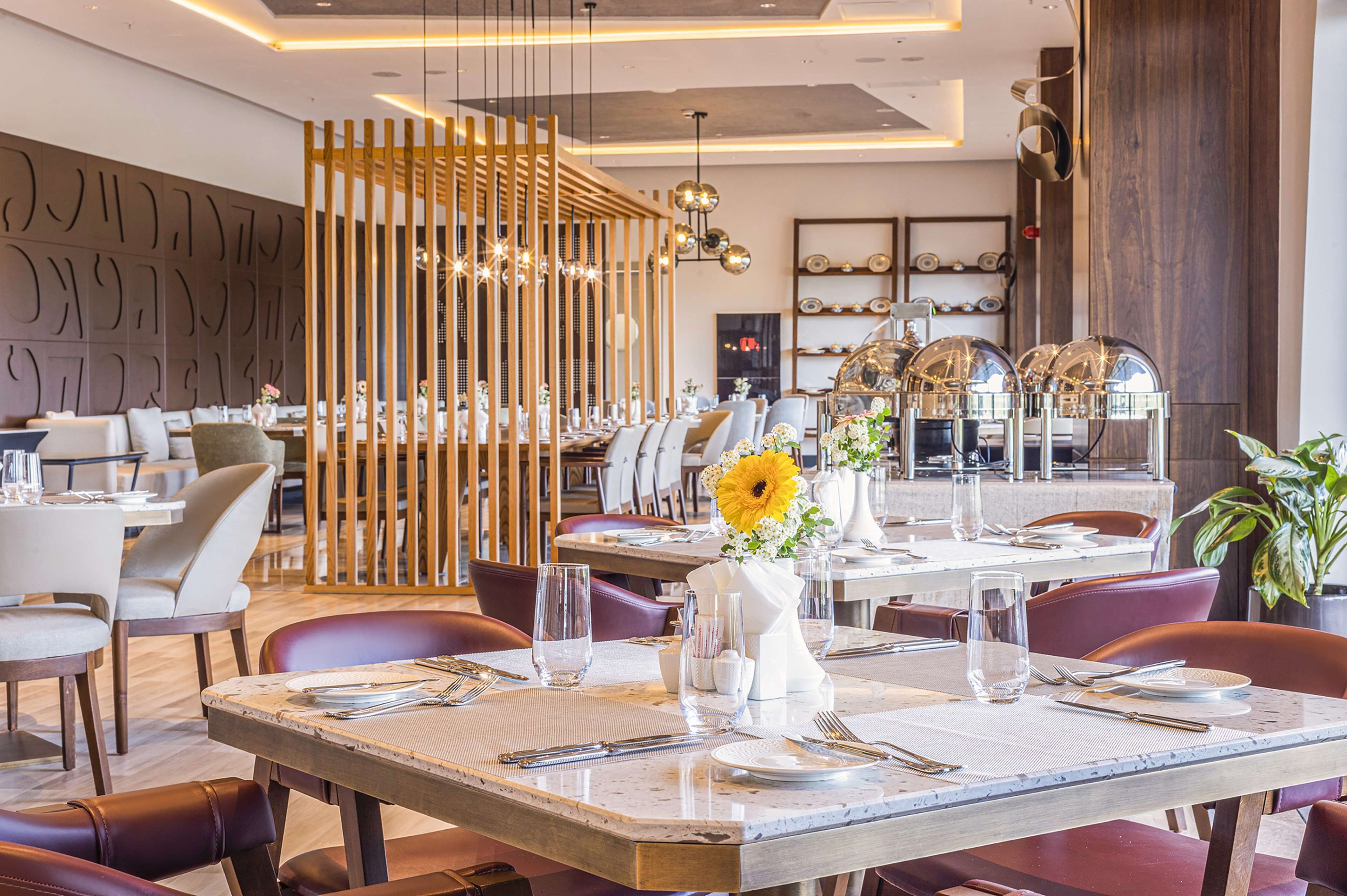 A modern restaurant with wooden partitions, marble tables, and a variety of seating options.