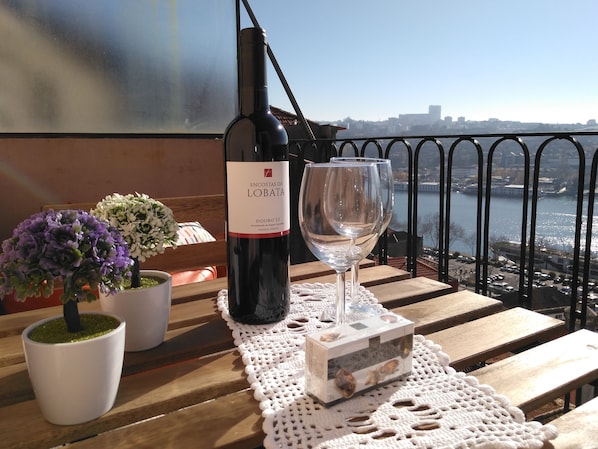 A table with a bottle of wine, a glass, and decorative items on a balcony overlooking a cityscape.