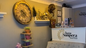 A cozy lounge area with a large wall clock, a sofa, a coffee table, and decorative items including a sculpture and a clock.