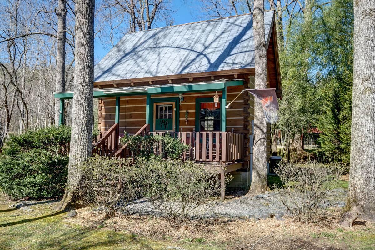 A log cabin with a porch, surrounded by trees and a clear sky.