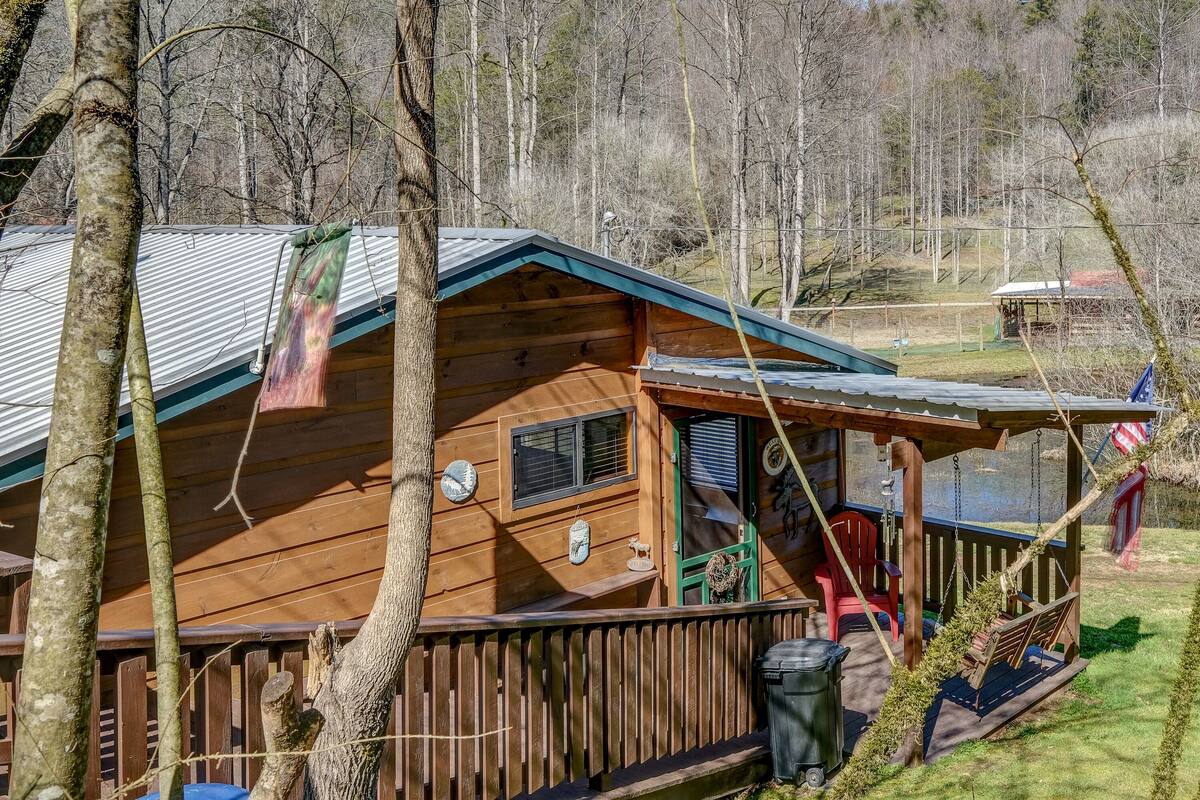 A wooden cabin with a porch, a swing, and a view of the surrounding forest.