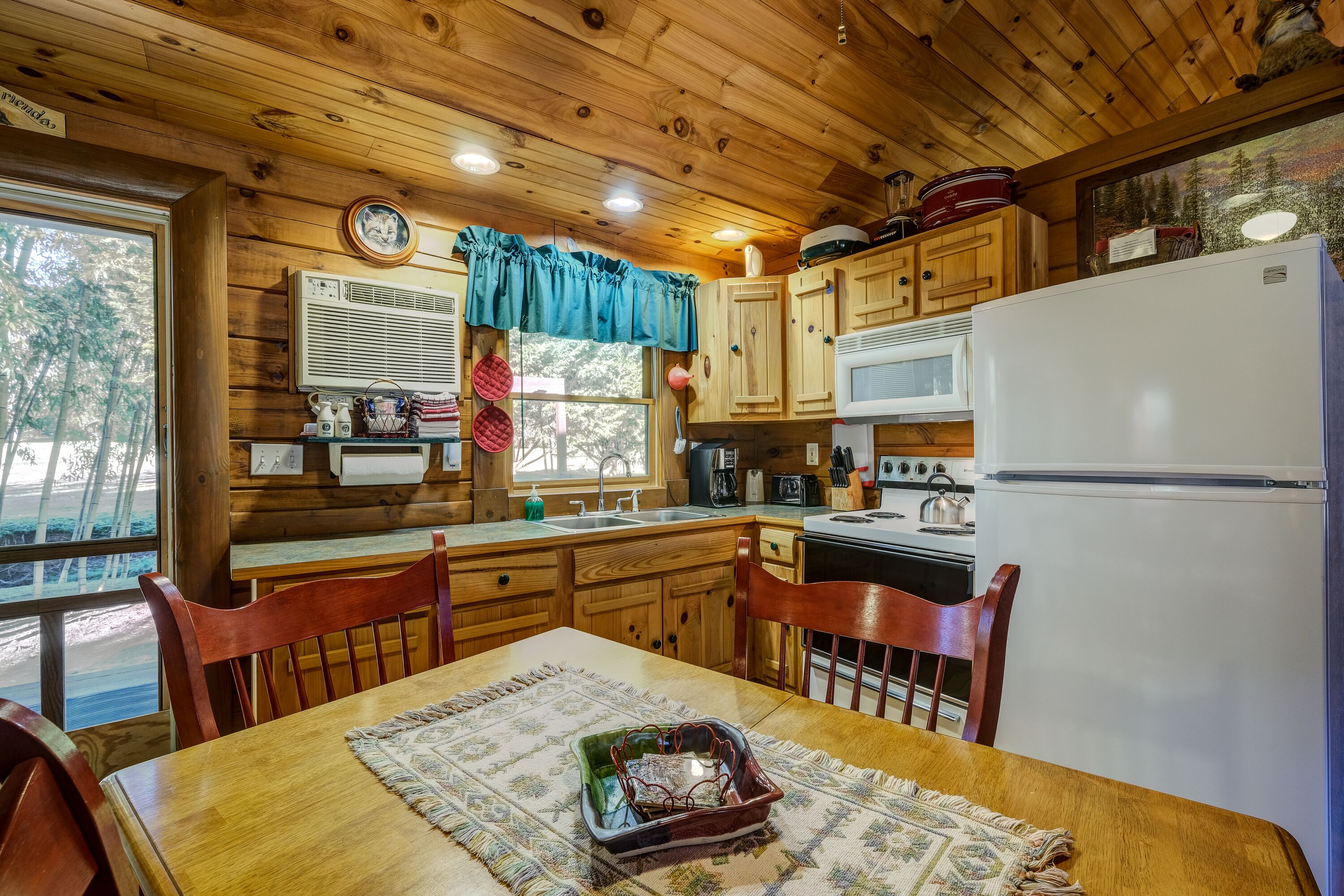 Une cuisine rustique aménagée dans une cabane en bois, avec une table à manger, des chaises, un réfrigérateur et des placards en bois.
