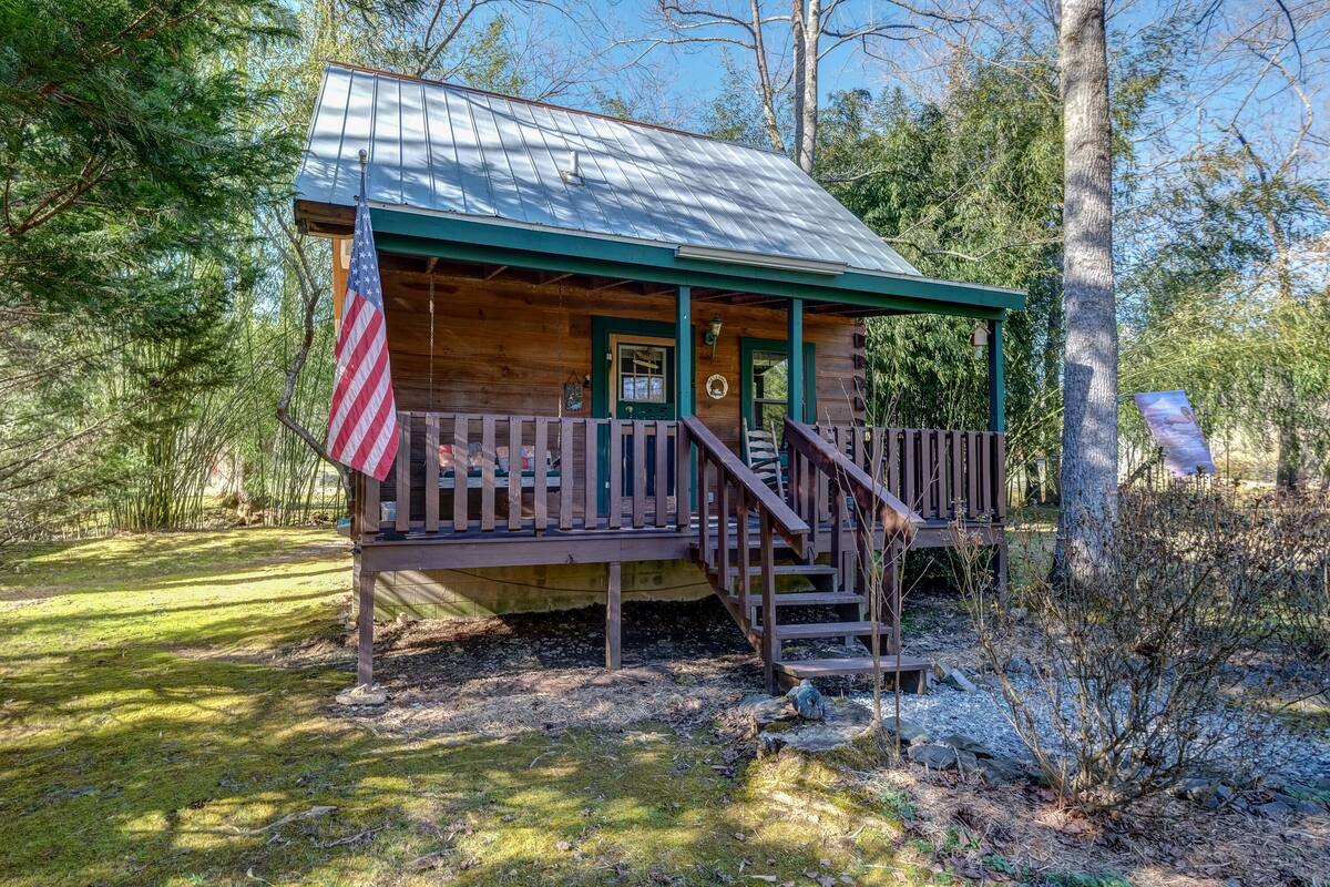 A rustic cabin with a porch, a flag, and a wooden deck.