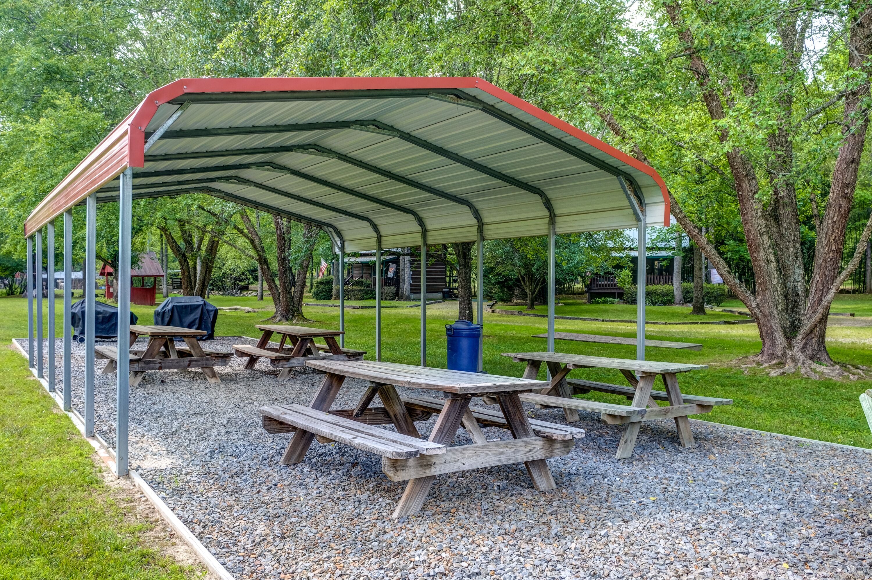 A covered picnic area with benches and a trash can.