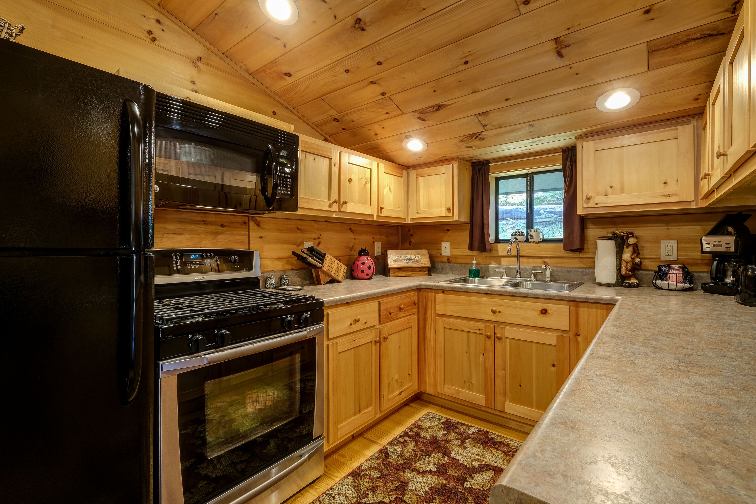 A modern kitchen with wooden cabinets, a black refrigerator, a stove, and a microwave.