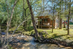 A cabin surrounded by trees and a small stream. - Cobb Creek Cabins (Murphy)