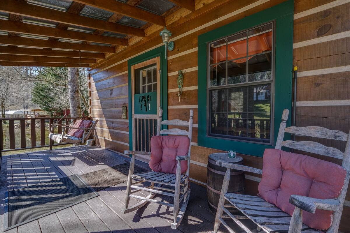A wooden cabin with a porch, rocking chairs, and a table.