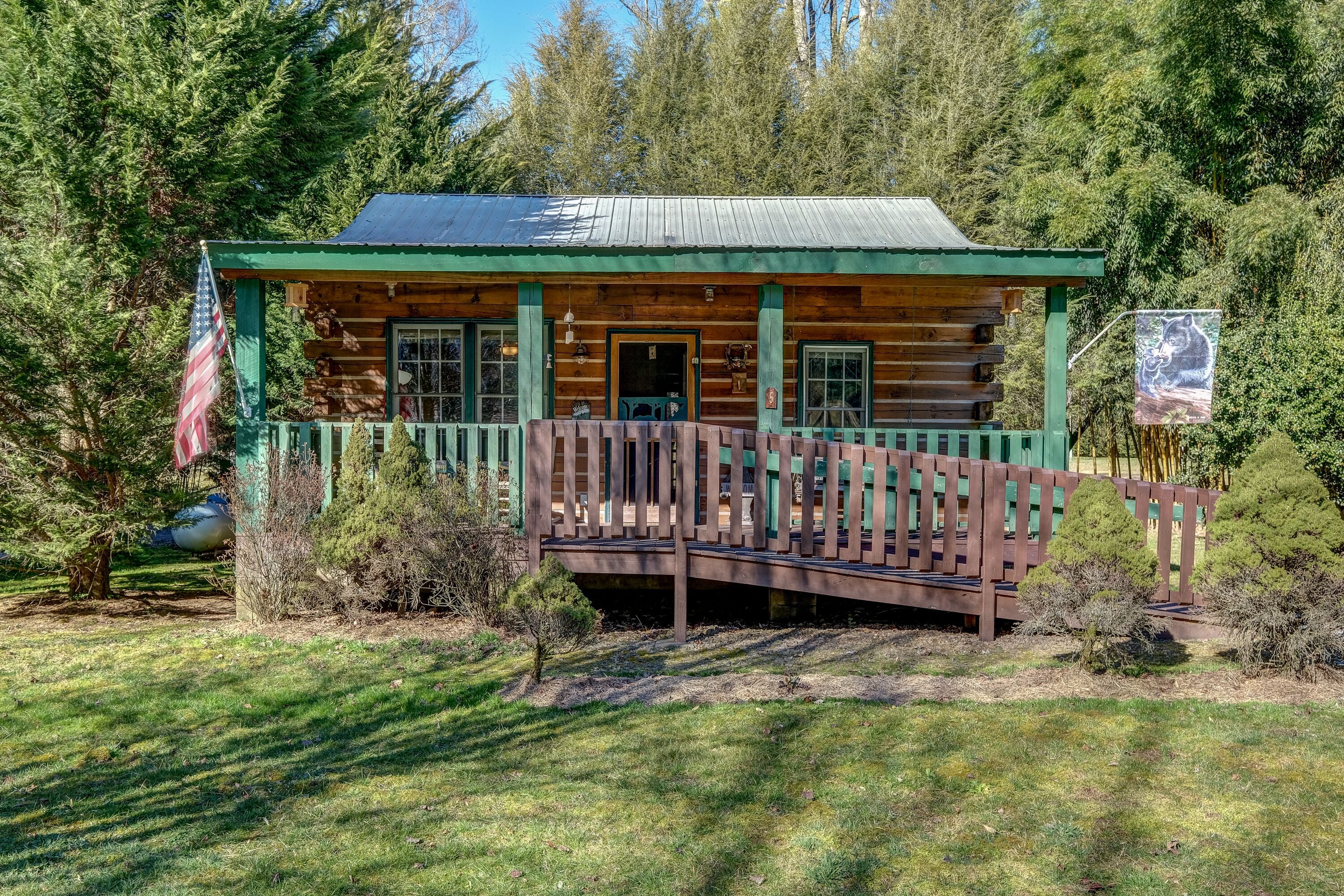 A rustic log cabin with a porch and a small bridge leading to the entrance.