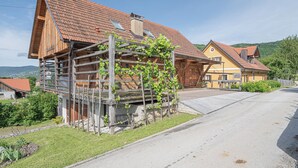 A wooden house with a red-tiled roof, a stone foundation, and a wooden pergola with climbing plants. - Traditional House Kal Garden & Jacuzzi (Semič)