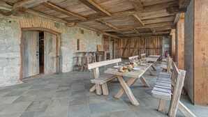 A rustic dining area with wooden benches and tables, stone walls, and a wooden ceiling. - Traditional House Kal Garden & Jacuzzi (Semič)