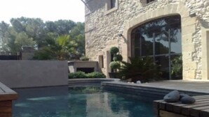 A stone building with a swimming pool and a wooden deck.
