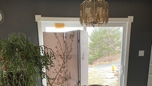 Un coin repas comprenant une table ronde en bois, quatre chaises en bois, un lustre et une plante en pot.