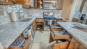A modern kitchen with granite countertops, wooden cabinetry, a stainless steel stove, and built-in appliances. - Elegant Art Deco Home designed with you in mind (El Paso)