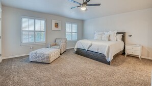 A bedroom with a bed, nightstand, chair, and ceiling fan. - Elegant Art Deco Home designed with you in mind (El Paso)