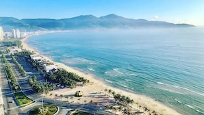 Un paysage urbain côtier avec une plage, des bâtiments et des montagnes.