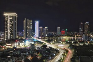 A nighttime cityscape with illuminated high-rise buildings, a river, and a busy highway with light trails. - Nature Hotel Da Nang (Da Nang)