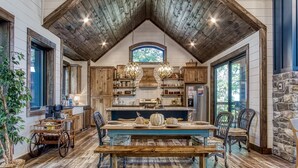 A rustic kitchen with wooden beams, a large island, and wicker furniture.