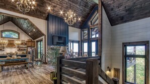 A spacious interior with a wooden staircase, a dining area with a bench, and a large window offering a view of the outdoors.